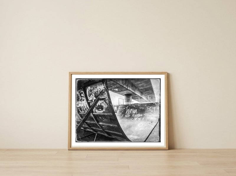 Skater ramp under the bridge — framed, leaning against the wall