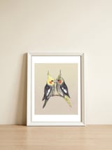 Two cute cockatiels — framed, leaning against the wall thumbnail
