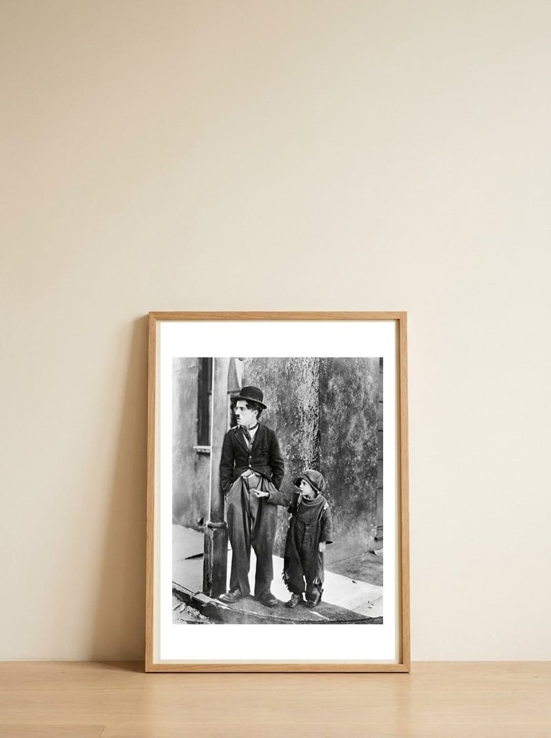 CHARLIE CHAPLIN and JACKIE COOGAN in THE KID (1921), directed by CHARLIE CHAPLIN. — framed, leaning against the wall