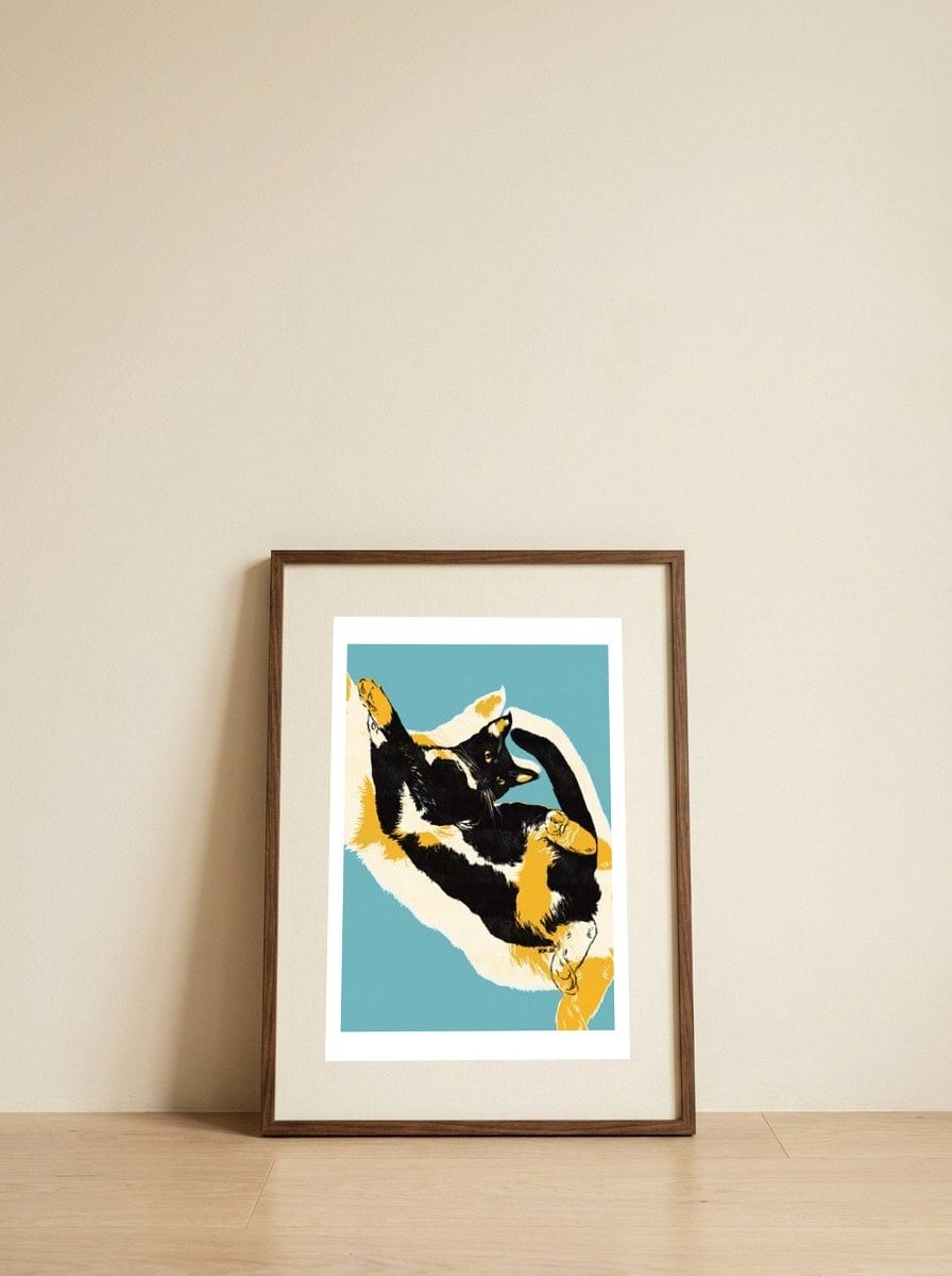 Playful Calico Cat — framed, leaning against the wall