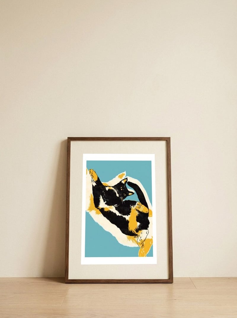 Playful Calico Cat — framed, leaning against the wall