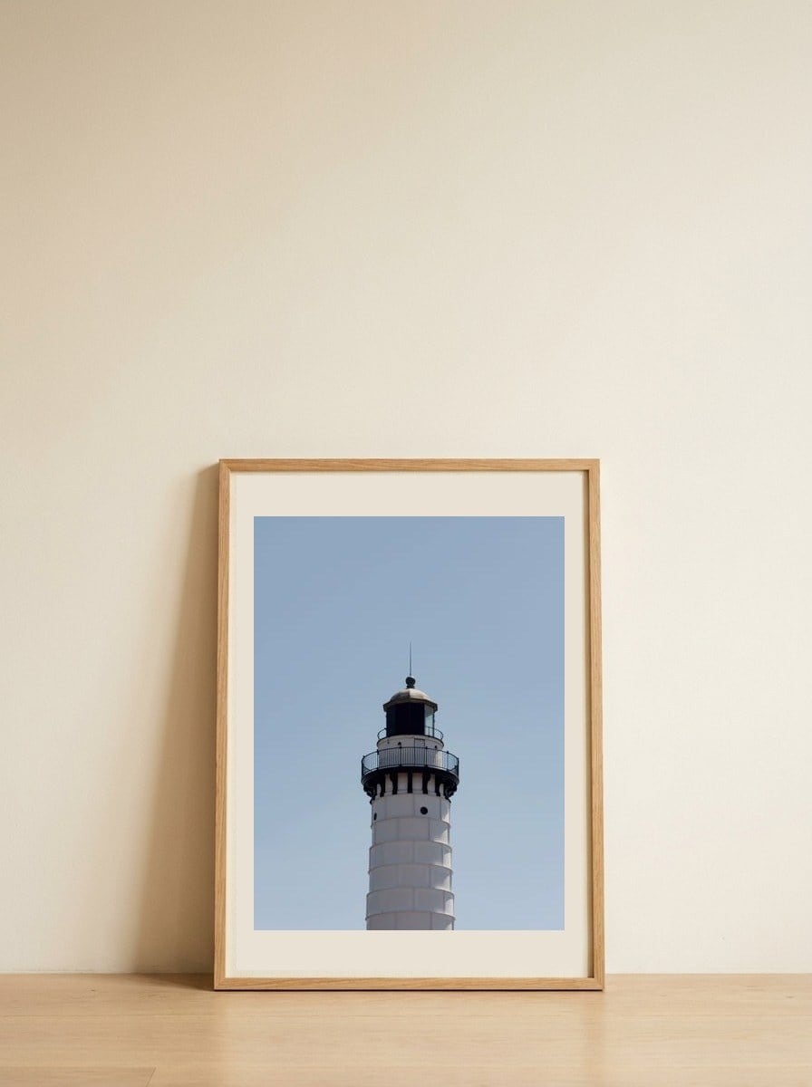 Lighthouse Under Blue Sky — framed, leaning against the wall