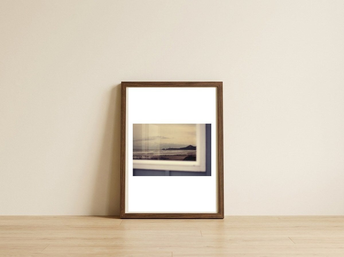 Lighthouse reflection — framed, leaning against the wall